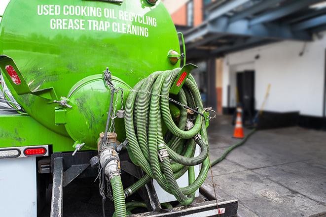 a professional plumber using a pump to empty a grease trap in Burlingame